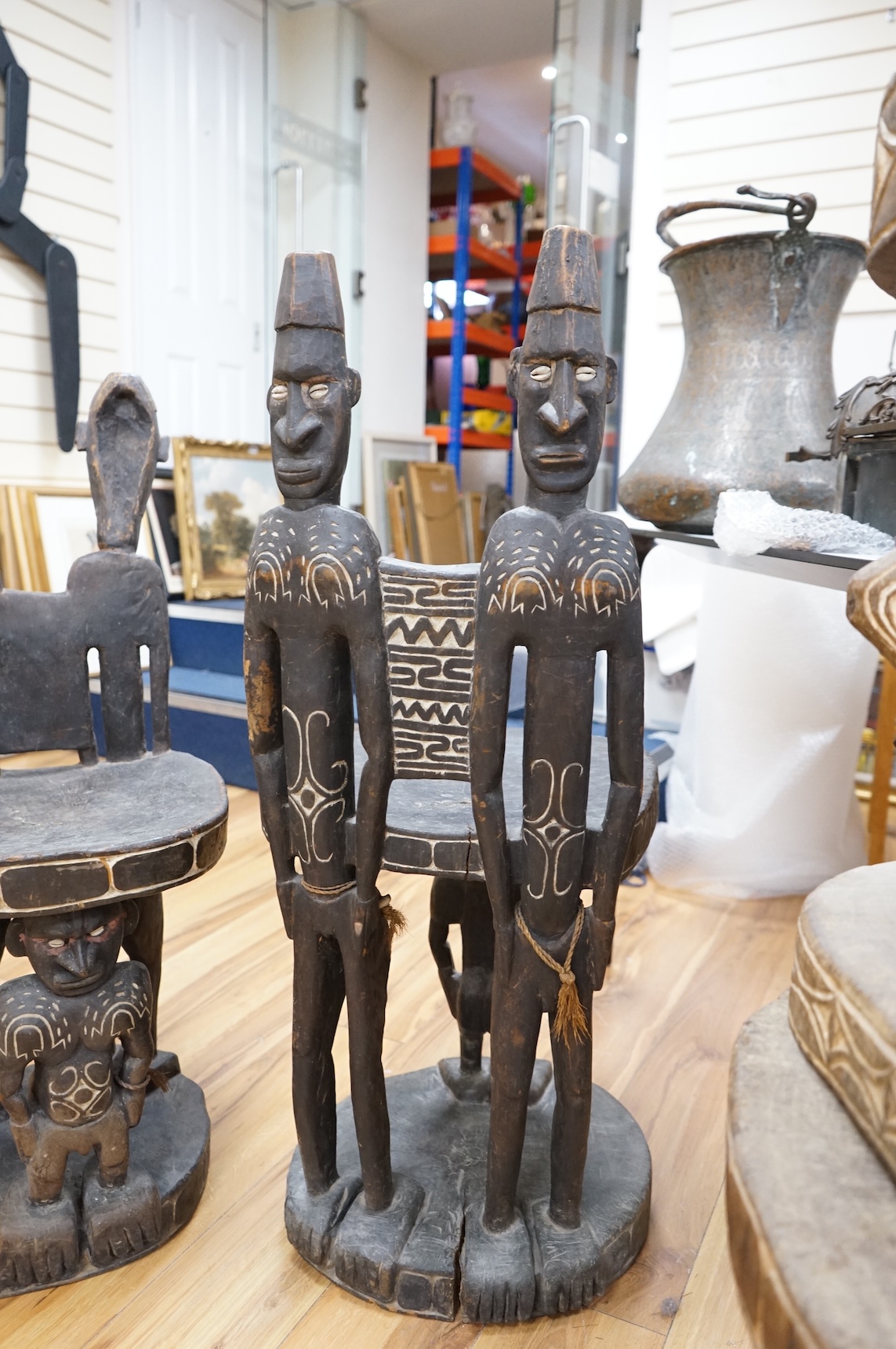 Papua New Guinea Sepik River, a near pair of ‘ceremonial’ figural chairs, each carved from a single section of a tree trunk with integral male and female backs and an castor figure front support with cowrie shell eyes. H